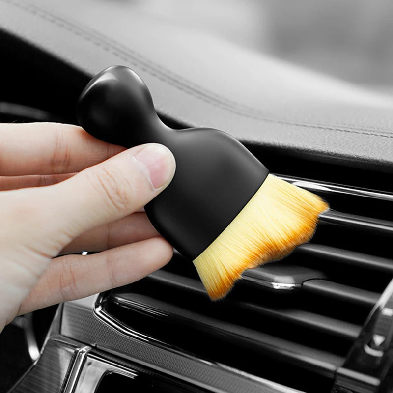 Staubpinsel reinigt die Lüftungsdüse im Auto